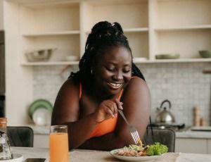 Woman smiling while eating healthy meal in kitchen