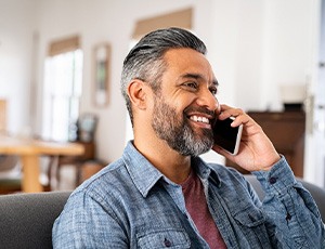 Man smiling while talking on phone at home