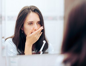 Woman holding her toothbrush, covering her mouth