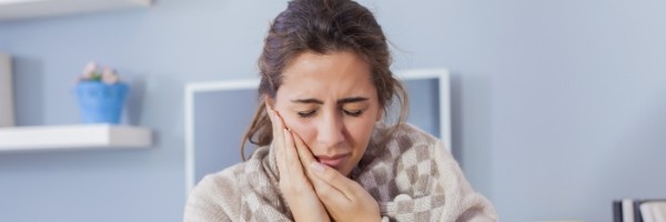 woman holding cheek in pain