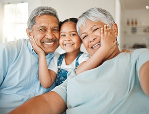 Grandparents and granddaughter smiling after seeing a MetLife dentist in Plano