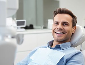 Happy male dental patient reclined in treatment chair