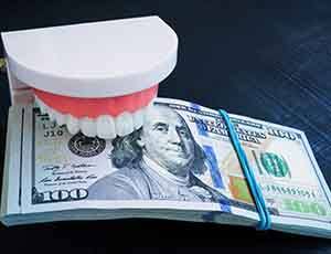 plastic teeth clamping down on a stack of money