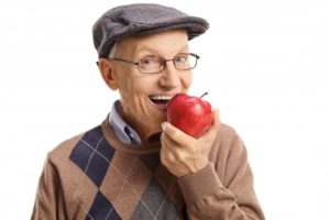 An older man eating an apple.